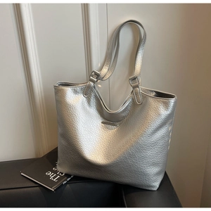Detailed close-up of metallic silver tote bag with lychee texture and metal bar detail