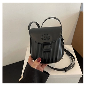 Detail of black pleated crossbody bag with premium leather texture and round logo accent