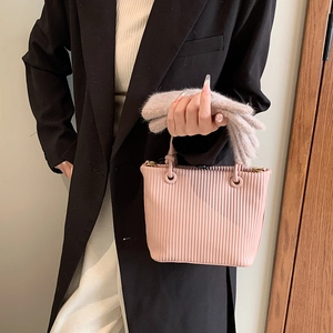 Vertical pleated pale pink bucket bag with accordion texture and chic round handle ring