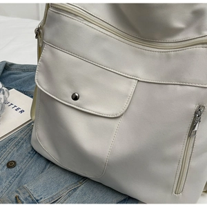 Close-up of off-white multi-pocket shoulder bag with silver snaps and nylon texture