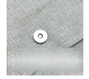 Detail of silver magnetic buckle on grey linen texture fabric of a crossbody bag