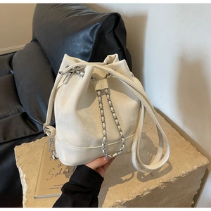Detailed close-up of cream leather bucket bag with silver chain and drawstring closure