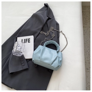 Detail view of light blue pleated handbag with braided handle and silver chain strap
