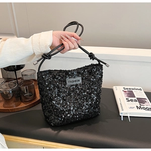 Detail of black sequined handbag with FASHION patch and slender chain strap