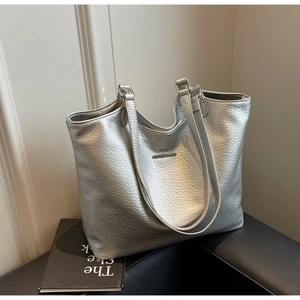 Close-up detail of silver metallic tote bag with lychee texture and rectangular metal logo