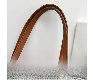 Detail of comfortable brown leather handles on a casual grey linen crossbody bag