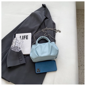 Detail of light blue pleated cloud bag with woven handle and silver chain strap