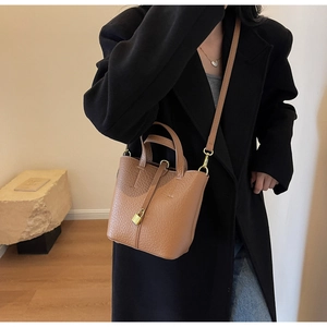 Detail view of the brown lychee leather bucket bag featuring a golden padlock and handles