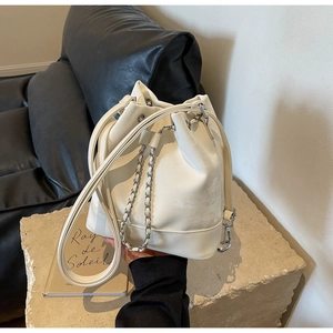 Detail of cream drawstring bucket bag showing leather texture and silver chain strap