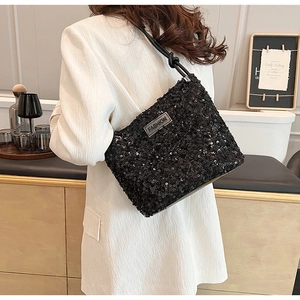 Detail of black sequined shoulder bag featuring a silver metal plate with fashion logo