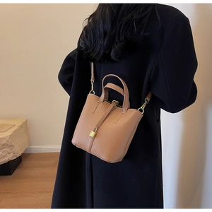 Brown lychee-grain leather bucket bag detail with gold lock and detachable shoulder strap