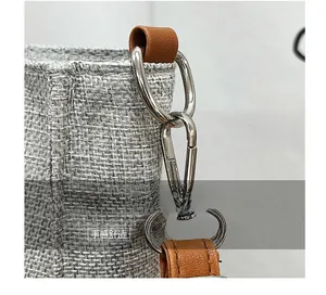 Close-up of the silver D-ring and metal lobster clasp on a grey linen fabric bag