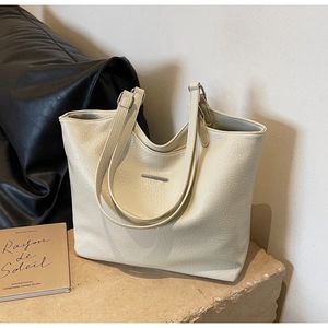 Detail of off-white pebbled leather tote bag with elegant silver metal bar and dual straps
