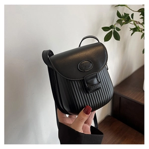 Detail of black crossbody bag featuring vertical striped embossing and fashion label