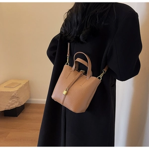 Brown bucket bag featuring pebble leather texture and golden padlock detail