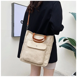 Detailed shot of a beige linen tote bag with brown leather handles and magnetic front pocket