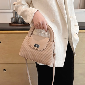 Elegant beige vertical textured crossbody bag with silver twist lock shown held by model