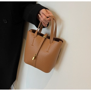 Close-up of brown pebbled leather bucket bag featuring gold padlock and drawstring detail