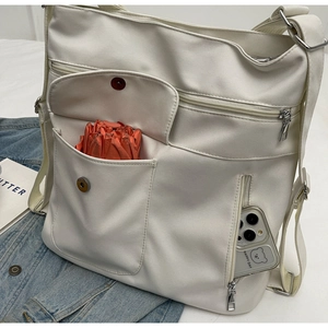 Detail view of cream canvas tote bag showing multiple pockets with umbrella and phone storage