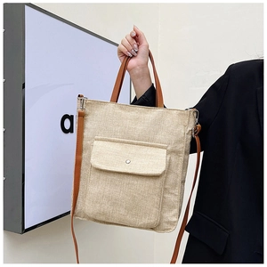 Detail of linen tote bag with brown leather handles and silver metal snap button