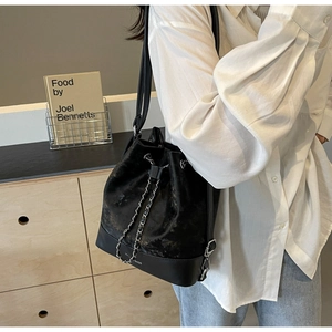 Detail of a chic black velvet bucket bag with silver drawstring chain on a model