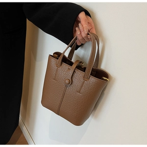 Detailed macro shot of caramel brown litchi grain leather on a stylish bucket handbag