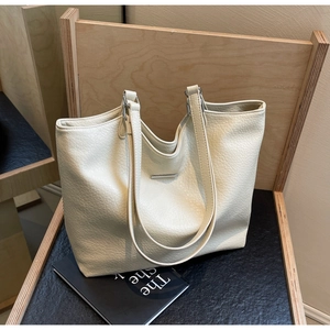 Detail of creamy white faux leather tote bag with lychee texture and metal accent