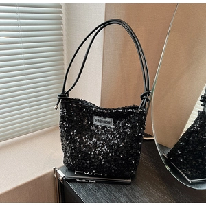 Detailed macro view of black sequin shoulder bag with leather knotted strap and fashion tag