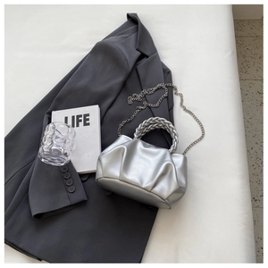 Detail of silver pleated cloud bag with woven handle and delicate metal chain