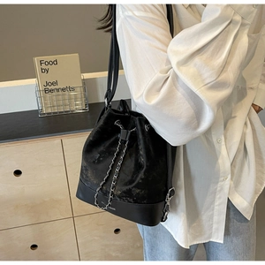 Detail of elegant black bucket bag with silver chain drawstring and mixed matte textures