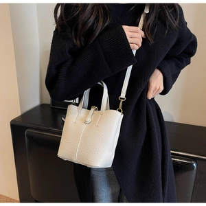 Detail of off-white lychee grain leather bucket bag with top handle and gold hardware
