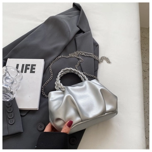 Close-up of silver pleated cloud bag with woven handle and metallic chain strap detail