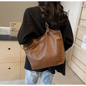 Brown leather tote bag showing large capacity and soft pebble texture on shoulder