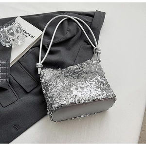 Detail of silver sequined handbag with knotted woven handle on elegant grey blazer fabric