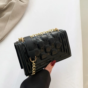 Minimalist black quilted flap bag with golden chain strap and refined leather finish