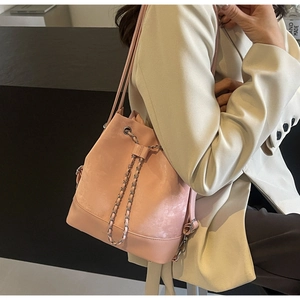 Close-up of pink bucket bag featuring a matte finish, drawstring closure, and metal chain