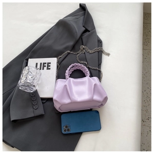 Lavender pleated mini bag with woven handle and metal chain on a grey blazer