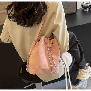 Detailed view of pink drawstring bucket bag with silver chain and suede texture