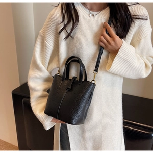 Detail of black lychee grain leather bucket bag with gold hardware and shoulder strap
