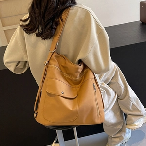 Large caramel tote bag with multiple pockets and adjustable strap shown on model back