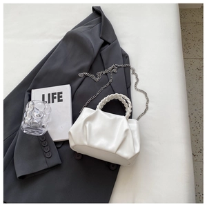Detail of white pleated cloud bag with braided handle and silver metal chain strap