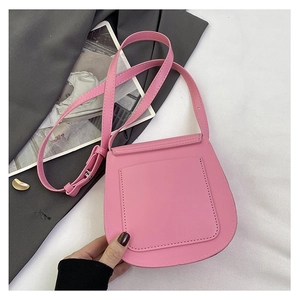 Pink saddle crossbody bag with fine stitching and adjustable strap on lifestyle background