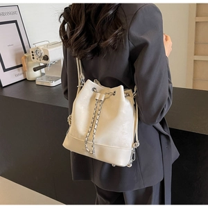 Chic beige leather bucket backpack featuring a drawstring closure and silver chain detail