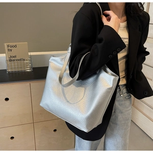 Close-up of silver tote bag featuring metallic lychee texture and dual shoulder straps