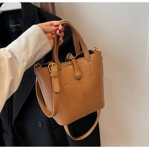 Detail of vintage brown bucket bag showing lychee grain leather texture and gold hardware
