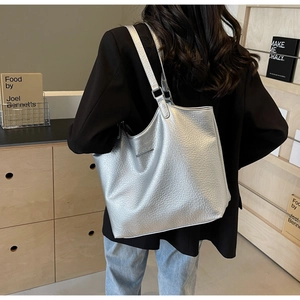 Detail of silver metallic tote bag showing textured pebble leather and sleek metal hardware