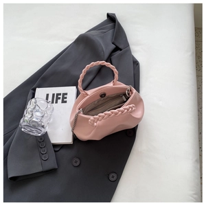 Detail of pink ruched handbag featuring braided handle and inner pocket structure