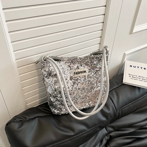 Silver sequin tote bag with chain strap and fashion label on a leather sofa