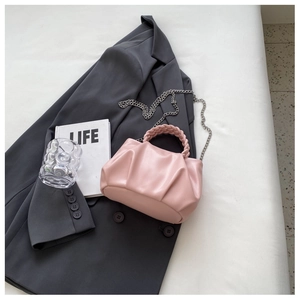 Pink pleated cloud handbag with woven handle and silver chain strap on a blazer