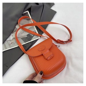 Detail of orange PU leather mini crossbody bag with vertical stripe embossing and round flap